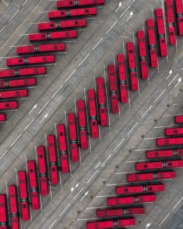 A captivating aerial photo of arranged red buses in an Islamabad parking lot.